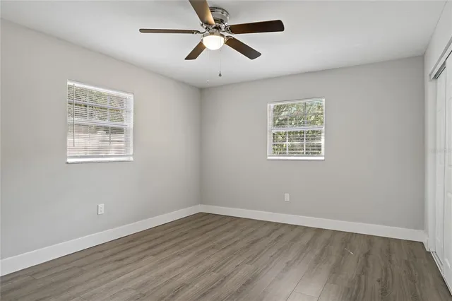 a view of an empty room with wooden floor and a window