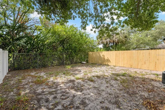 a backyard of a house with large trees and wooden fence