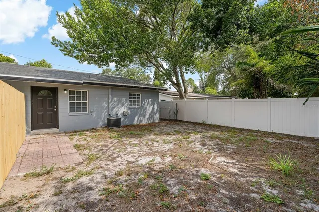a backyard of a house with large trees and brick walls
