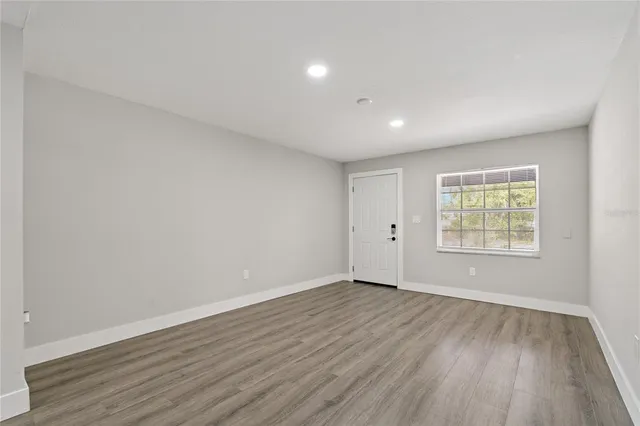 a view of an empty room with wooden floor and a window