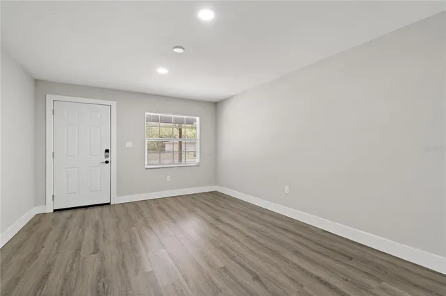 a view of an empty room with wooden floor and a window
