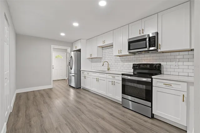 a kitchen with stainless steel appliances white cabinets and a stove top oven