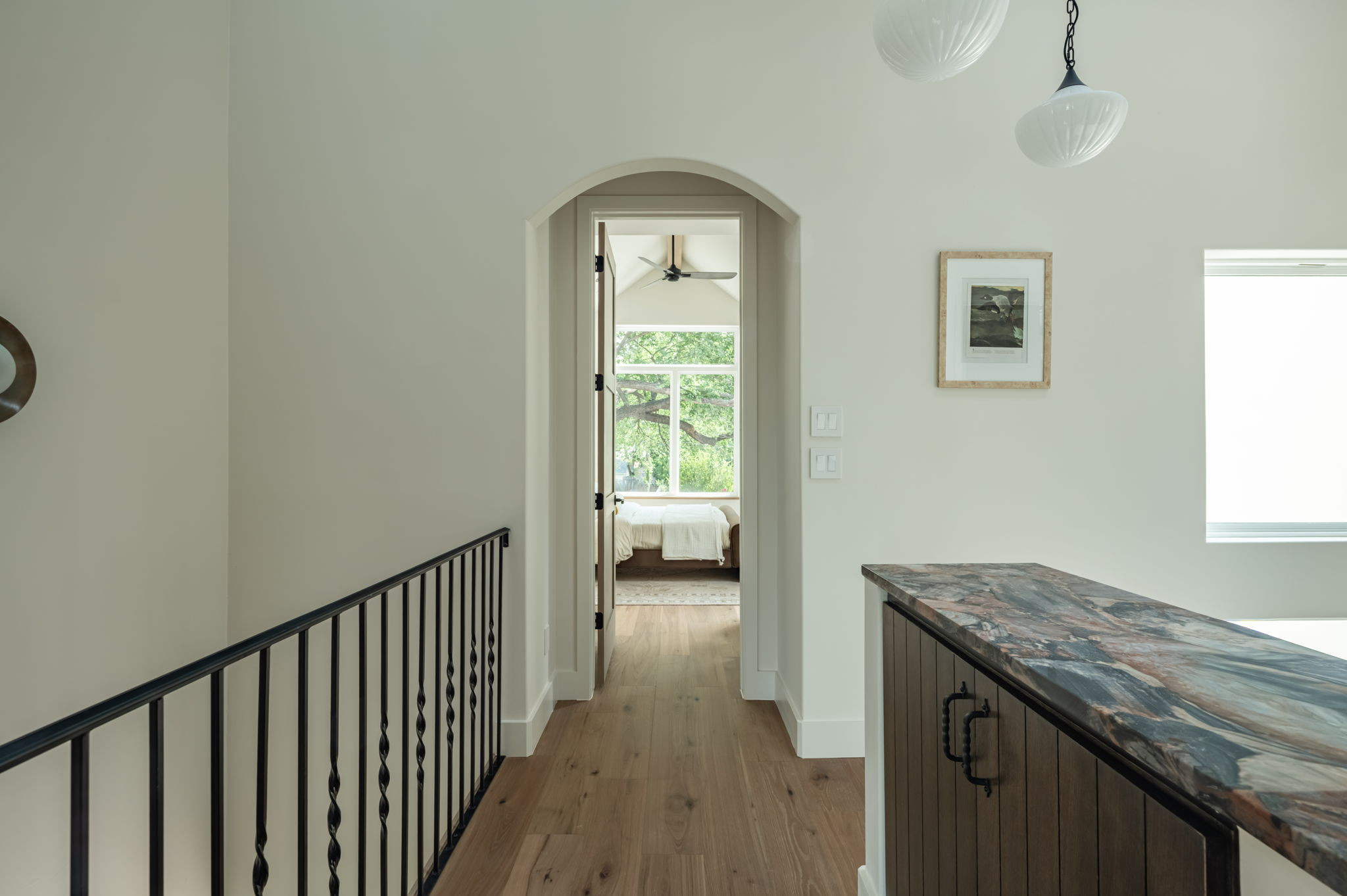 4713 Bolm Road Austin, TX 78702 - Photo 22 of 40 Upper level hallway featuring wood-finish flooring, a wrought iron railing, and an arched doorway