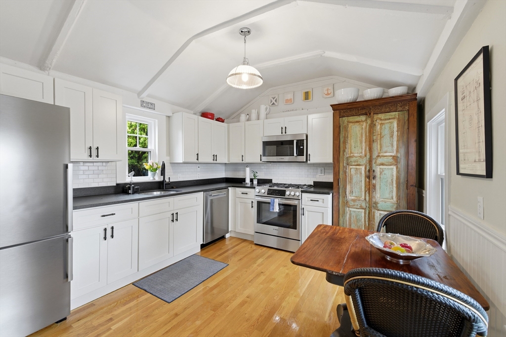 8 Linden Street Marblehead, MA 01945 - Photo 7 of 41 a kitchen with stainless steel appliances granite countertop a sink a stove a refrigerator cabinets and a dining table with wooden floor