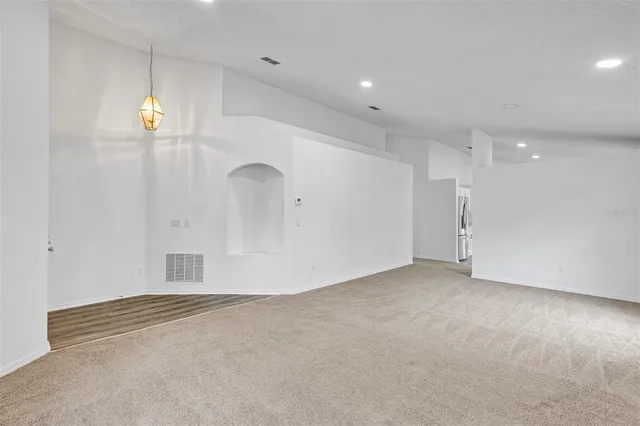 an empty room with chandelier fan and windows