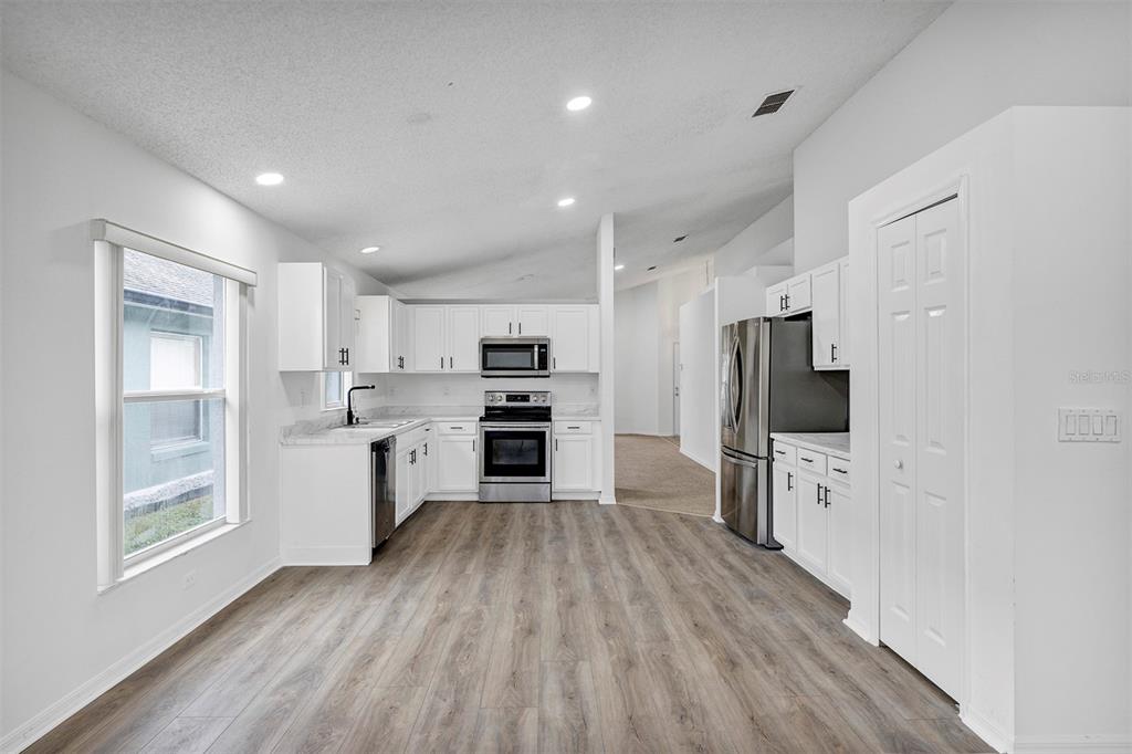 4254 Northern Dancer Way Orlando, FL 32826 - Photo 8 of 38 a kitchen with white cabinets stainless steel appliances and window