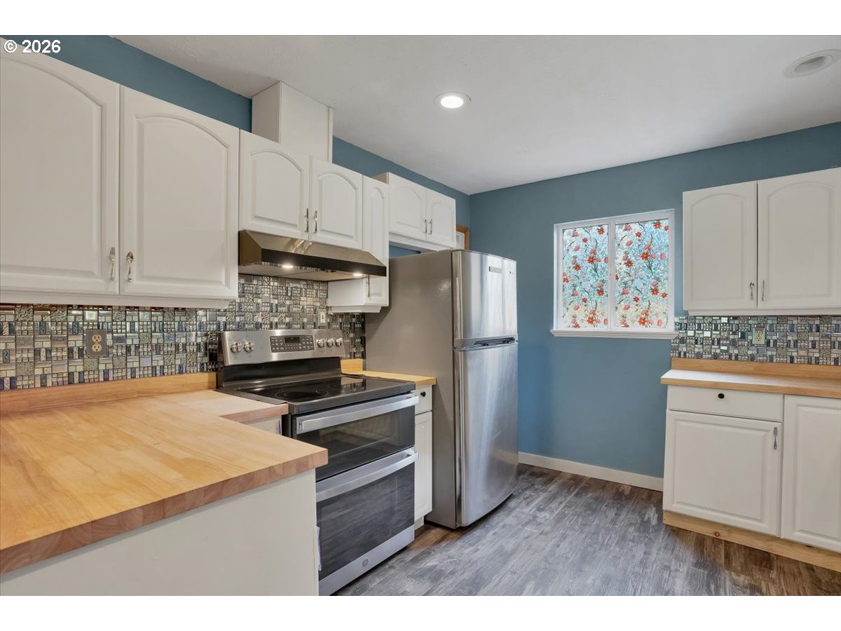 566 North Bear Creek Road Otis, OR 97368 - Photo 12 of 40 a kitchen with granite countertop a refrigerator stove and white cabinets
