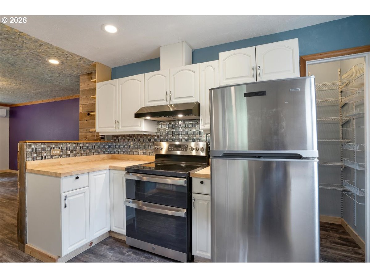 566 North Bear Creek Road Otis, OR 97368 - Photo 14 of 40 a kitchen with refrigerator cabinets and wooden floor