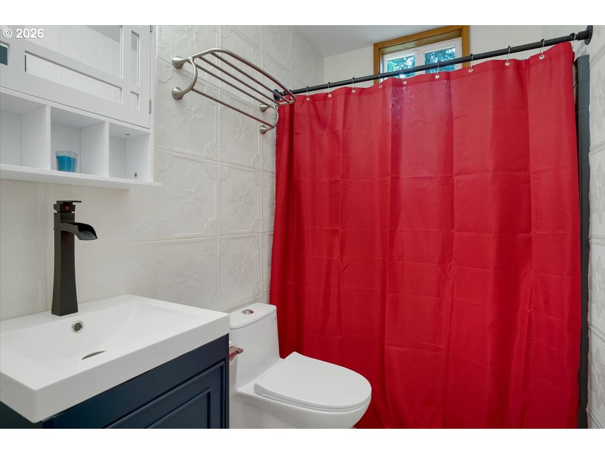 566 North Bear Creek Road Otis, OR 97368 - Photo 27 of 40 a bathroom with a sink a toilet and shower curtain