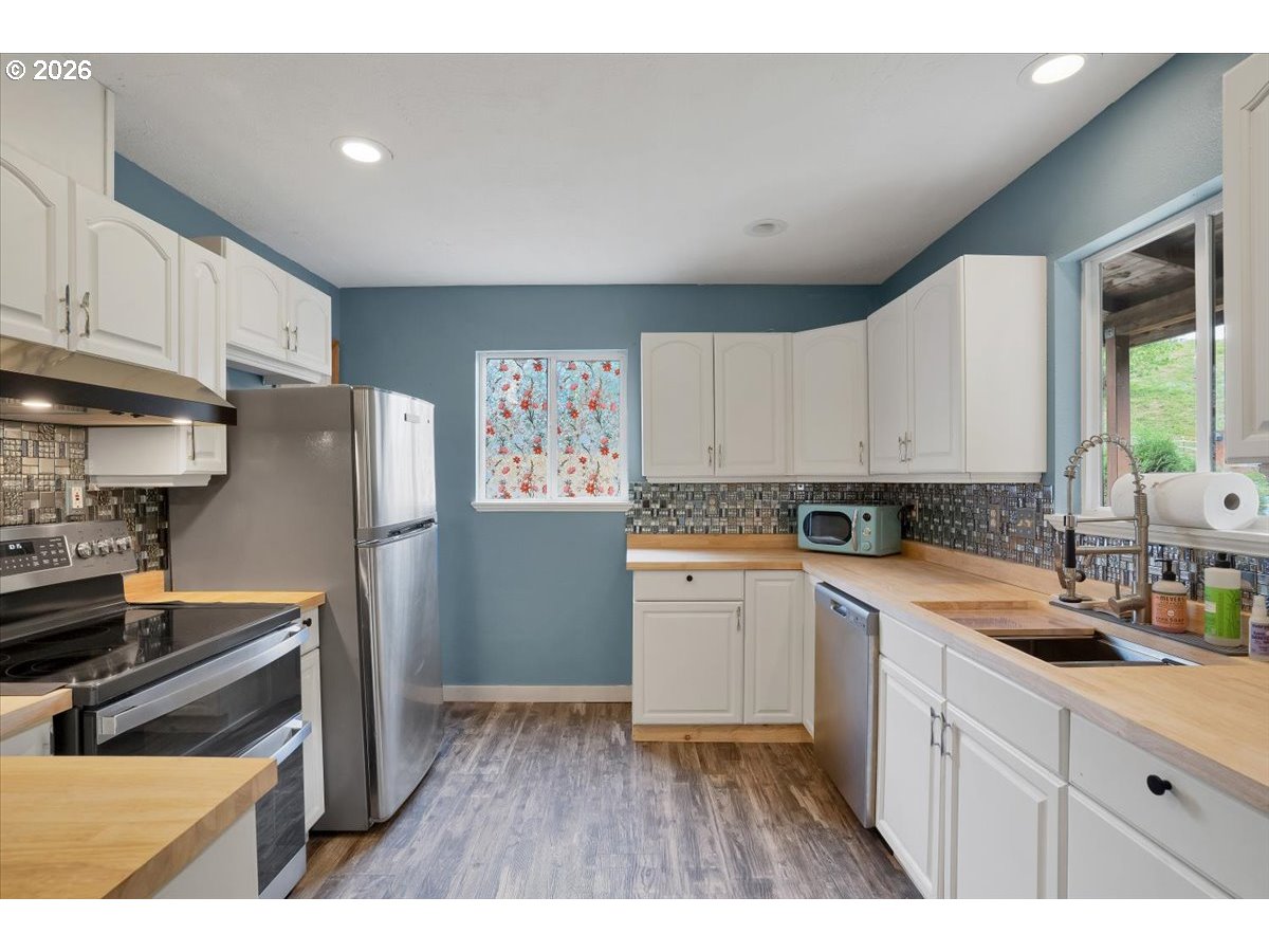 566 North Bear Creek Road Otis, OR 97368 - Photo 10 of 40 a kitchen with a refrigerator sink and white cabinets