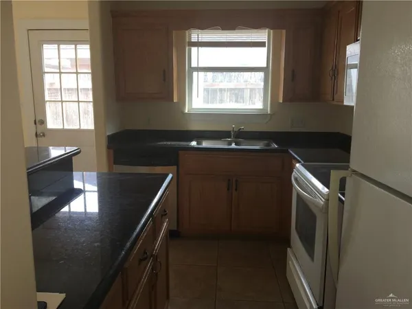 a kitchen with granite countertop a sink stove and refrigerator