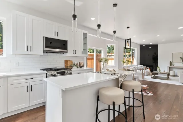 a kitchen with stainless steel appliances a stove a sink a microwave a center island and furniture