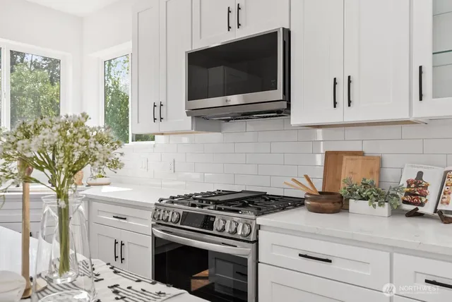 a kitchen with stainless steel appliances white cabinets and a stove top oven