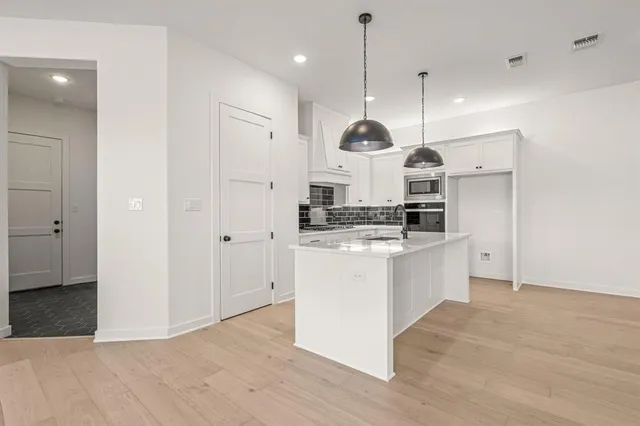 a kitchen with kitchen island stainless steel appliances a stove a sink cabinets and a wooden floor