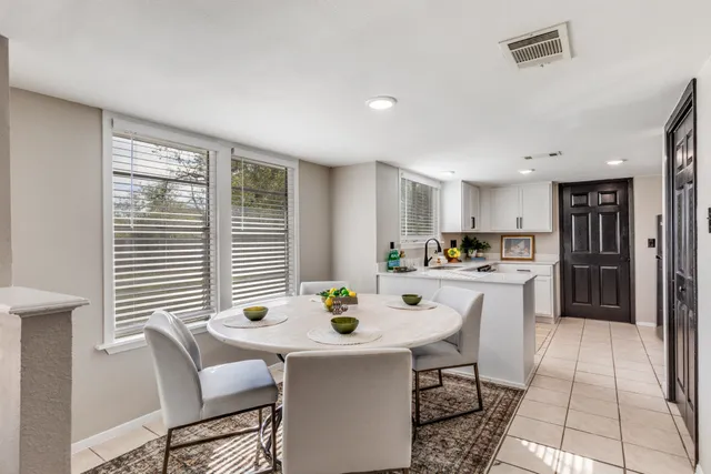 a kitchen with a dining table chairs and refrigerator