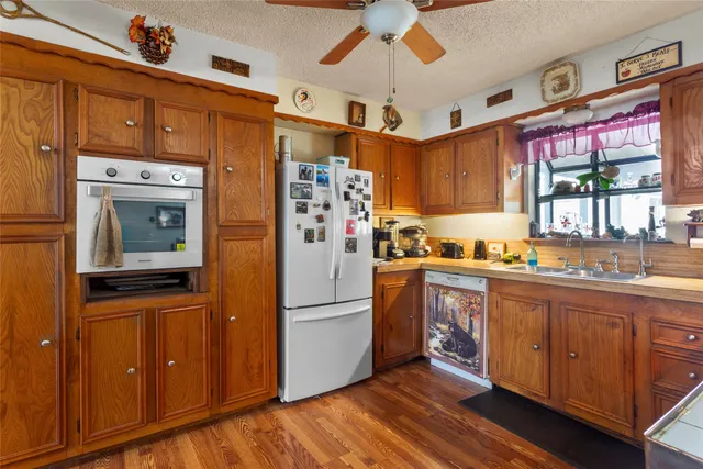 a kitchen with granite countertop stainless steel appliances a refrigerator cabinets and wooden floor