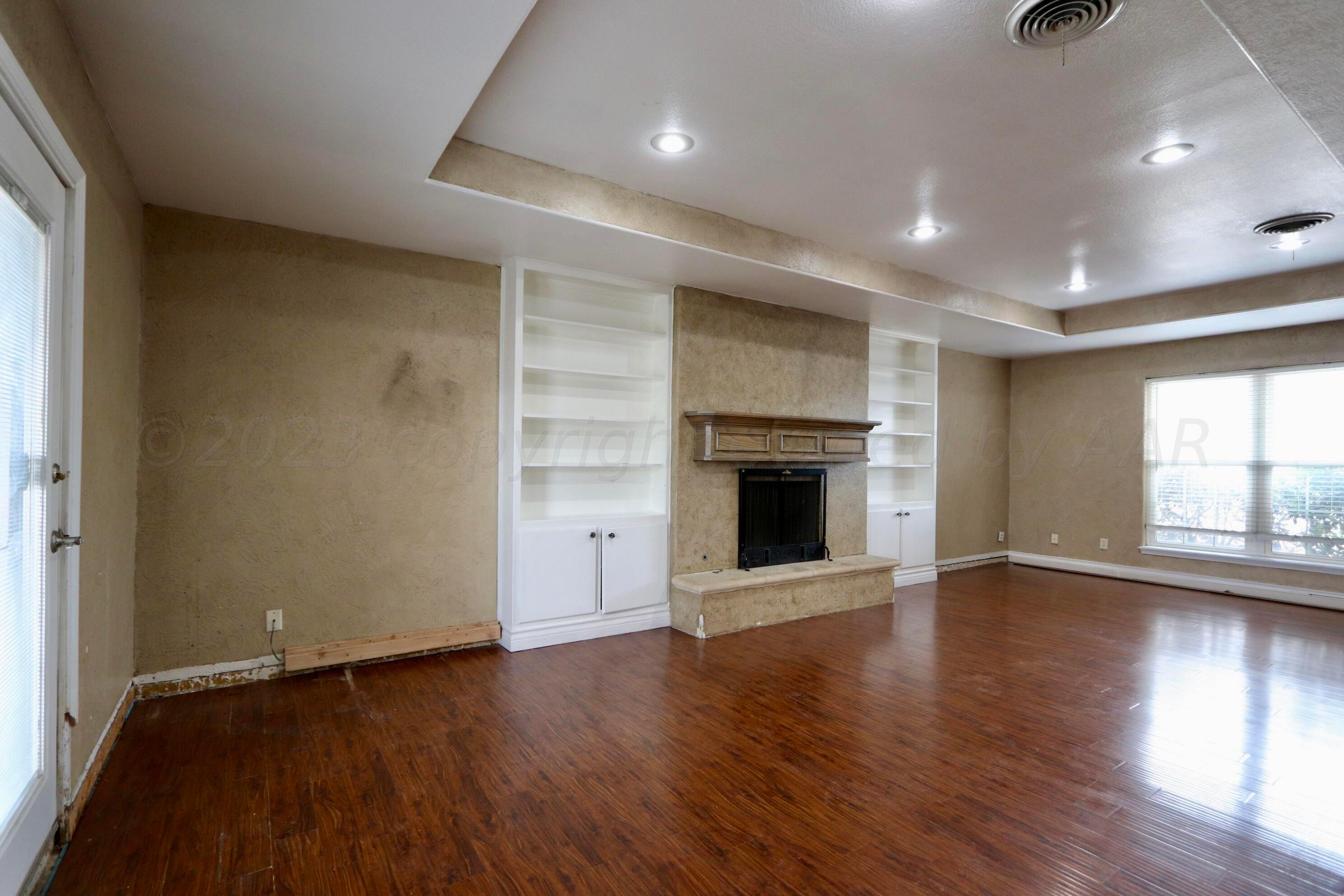 7916 Fenley Drive Amarillo, TX 79121 - Photo 3 of 23 an empty room with wooden floor and fireplace