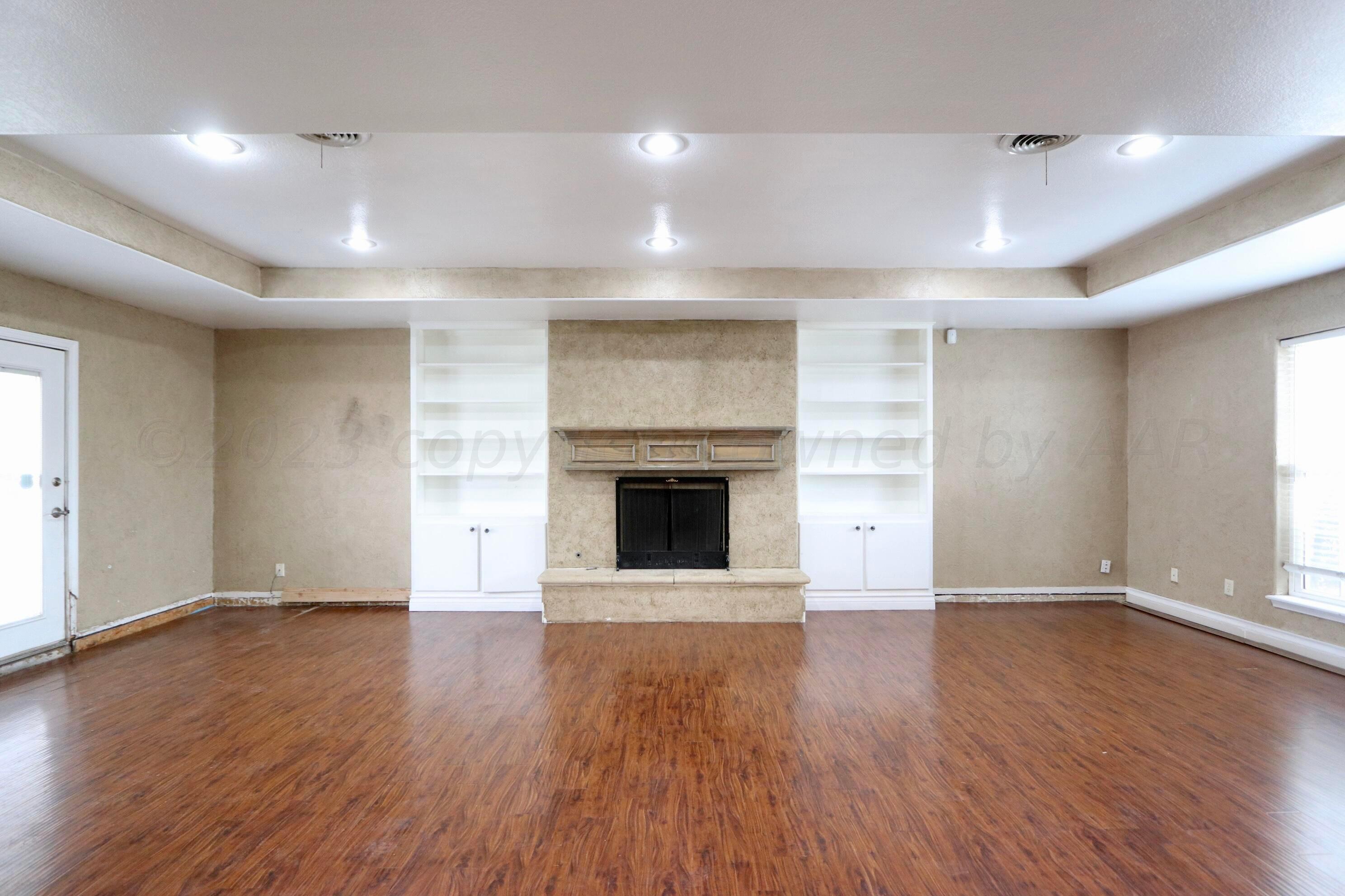 7916 Fenley Drive Amarillo, TX 79121 - Photo 4 of 23 an empty room with wooden floor and fireplace