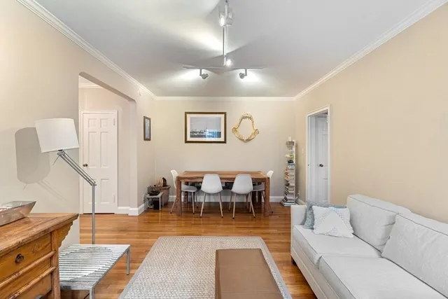 a living room with furniture and a dining table with wooden floor