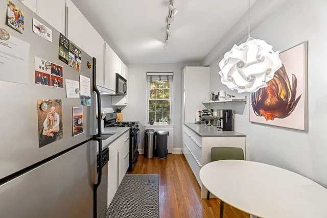 a kitchen with stainless steel appliances a stove a refrigerator a sink a dining table and chairs with wooden floor