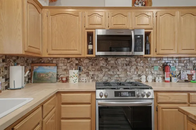 a kitchen with stainless steel appliances granite countertop a stove top oven a sink dishwasher and a microwave oven with cabinets