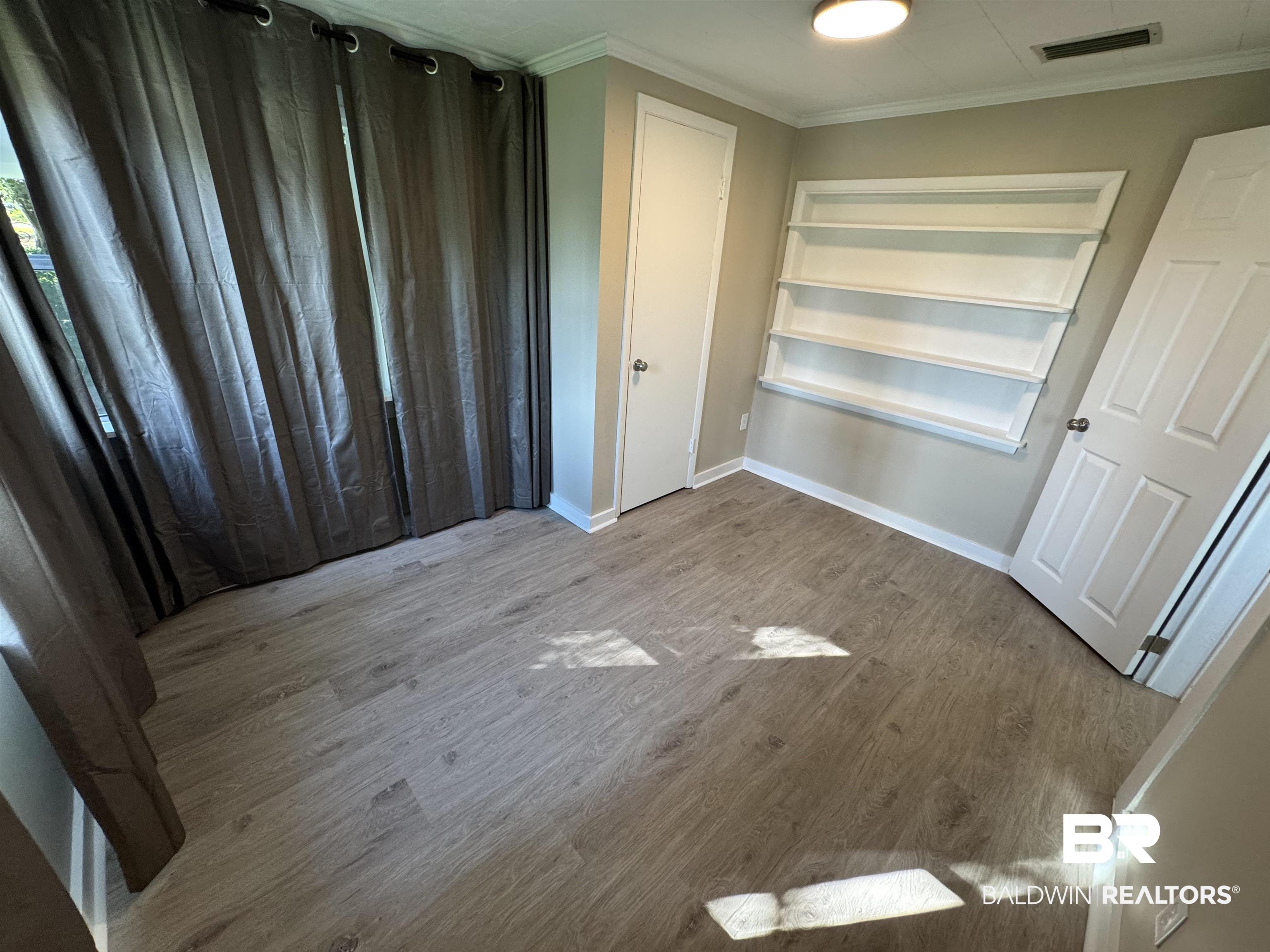 22640 Racine Street Robertsdale, AL 36567 - Photo 38 of 40 Unfurnished bedroom featuring ornamental molding and wood finished floors