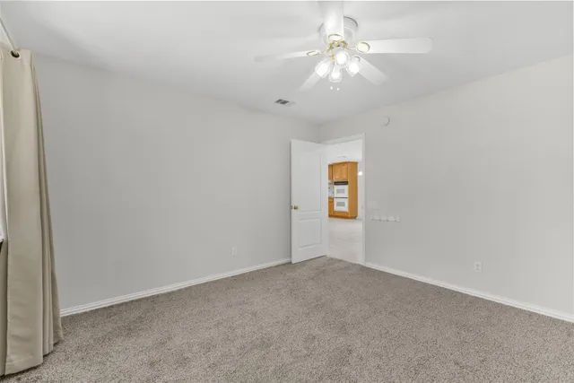 an empty room with a ceiling fan and a window