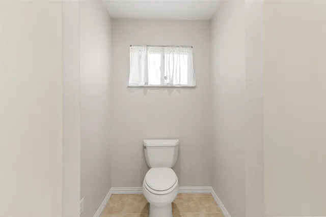 a white toilet sitting in a bathroom next to a window