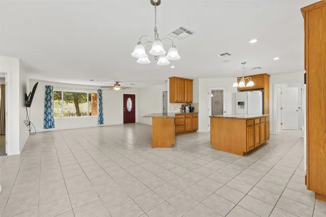 a view of a kitchen with kitchen island stainless steel appliances granite countertop a stove and a sink with chandelier