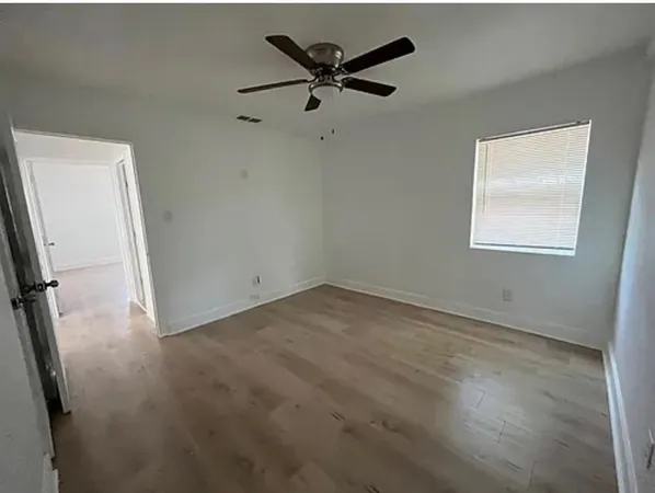 an empty room with windows and fan
