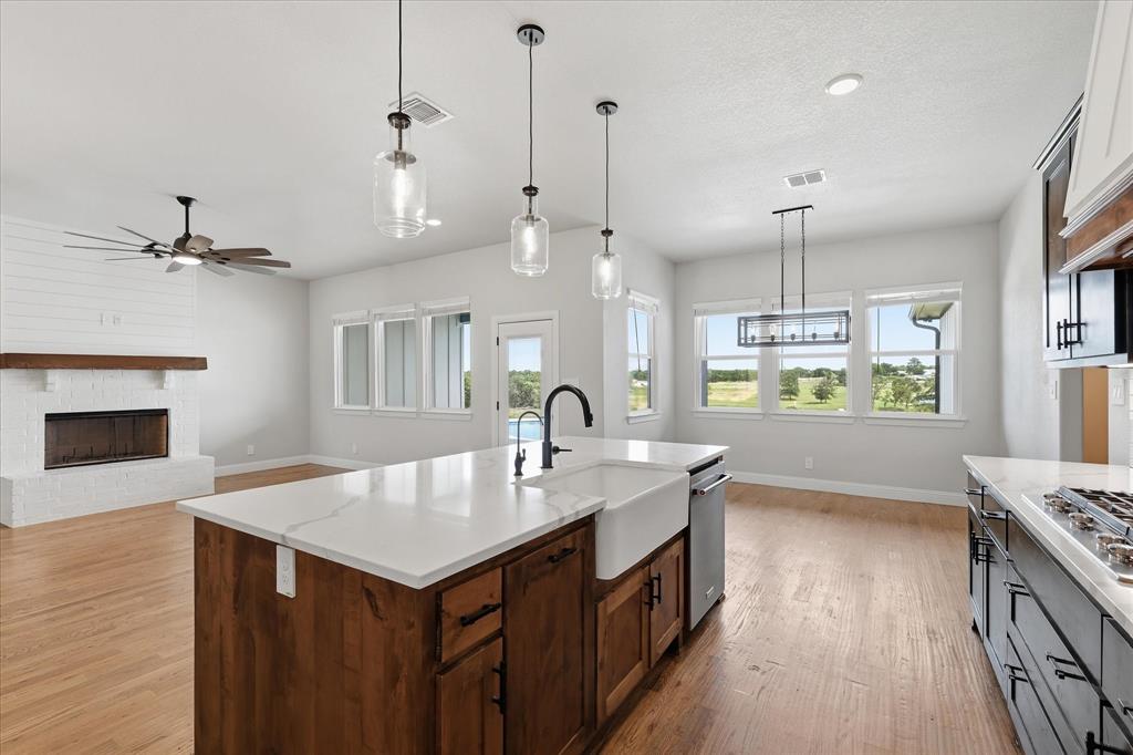 120 Grace Vw Road Weatherford, TX 76088 - Photo 15 of 40 Open-concept living space featuring a central kitchen island with a farmhouse sink, stainless steel appliances, and wood-finish flooring