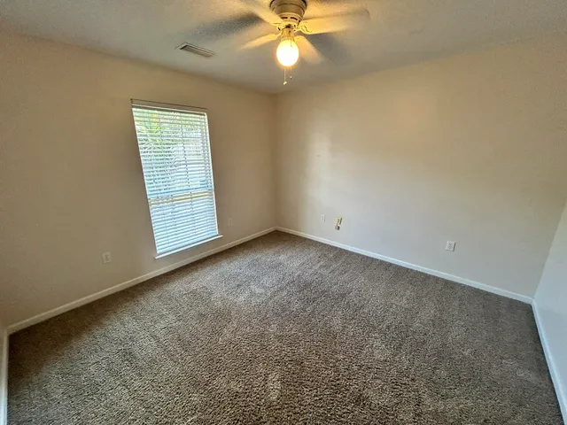 an empty room with windows and fan