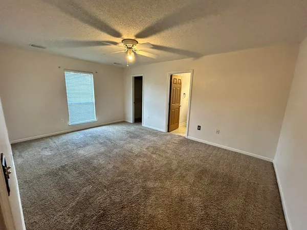 an empty room with windows and fan