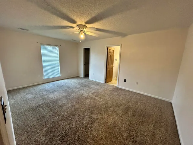 an empty room with windows and fan