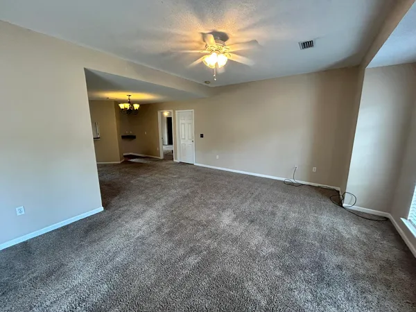 an empty room with a chandelier fan and a window