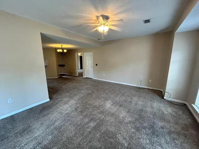an empty room with a chandelier fan and a window