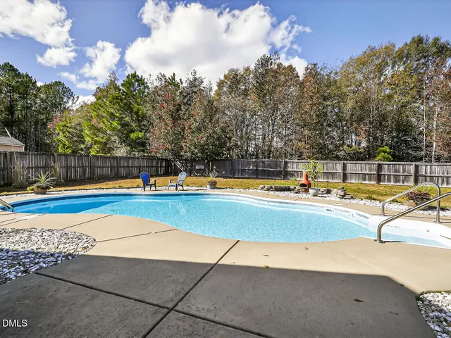 a view of swimming pool with seating area and trees in the background