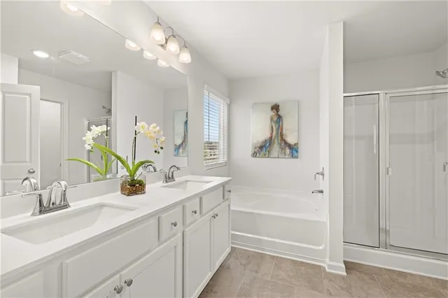 a bathroom with a double vanity sink a mirror a bathtub and next to a window