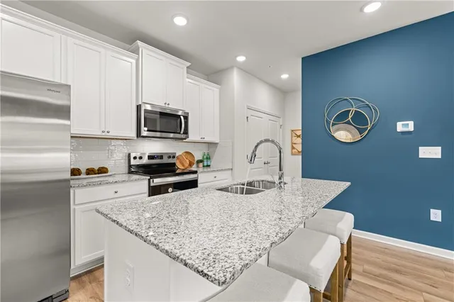 a kitchen with granite countertop a stove a sink a microwave a dining table and chairs