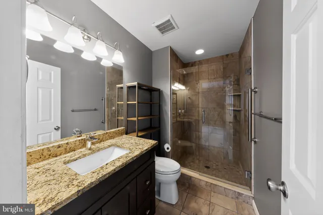 a bathroom with a granite countertop sink a toilet and shower