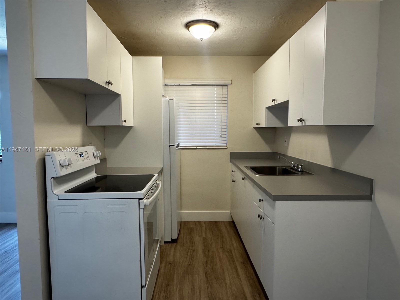 1310 West 29th Street, Unit 32 Hialeah, FL 33012 - Photo 5 of 11 a kitchen with a sink a stove and cabinets