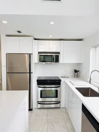 a kitchen with a sink a microwave a refrigerator and white cabinets