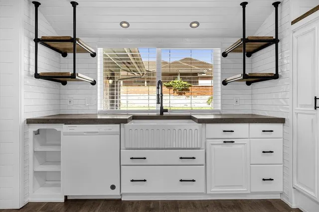 a kitchen with white cabinets and window