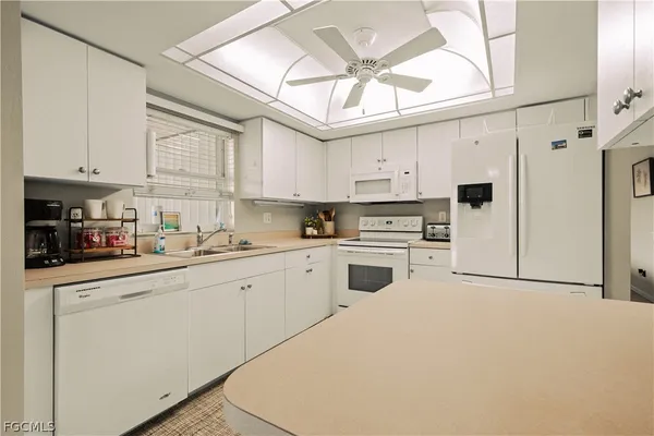 a kitchen with stainless steel appliances granite countertop a stove a refrigerator a sink dishwasher and white cabinets with wooden floor