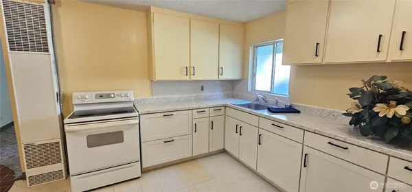 a kitchen with granite countertop white cabinets and white appliances