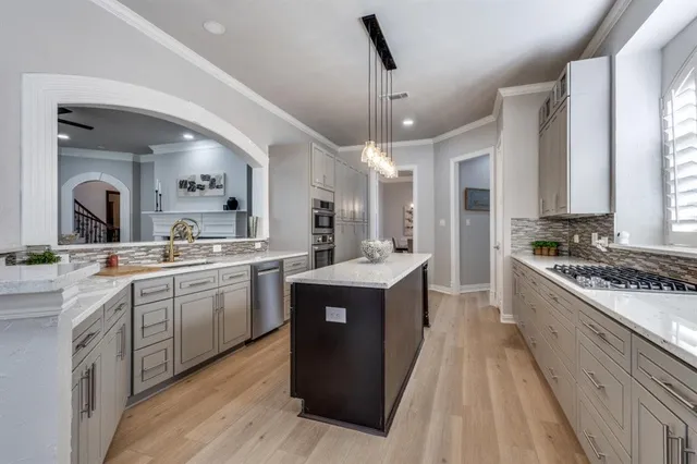 a kitchen with stainless steel appliances granite countertop a stove top oven a sink dishwasher and white cabinets with wooden floor