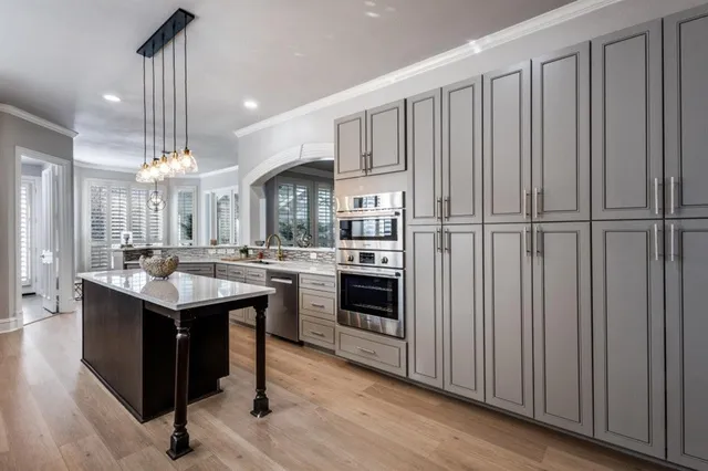 a kitchen with kitchen island granite countertop stainless steel appliances a sink a counter space and wooden floor