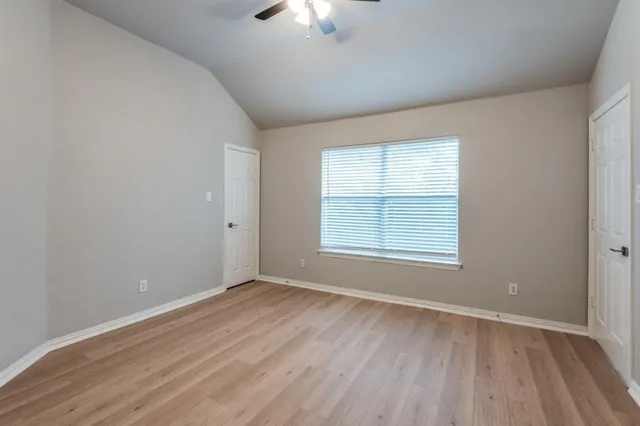 an empty room with wooden floor and windows