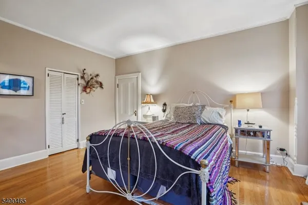 a bedroom with a bed a lamp and wooden floor