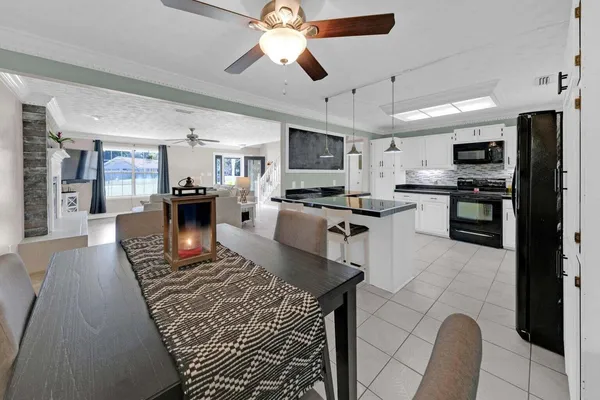 a large kitchen with stainless steel appliances granite countertop a stove top oven a sink dishwasher a dining table and chairs with wooden floor
